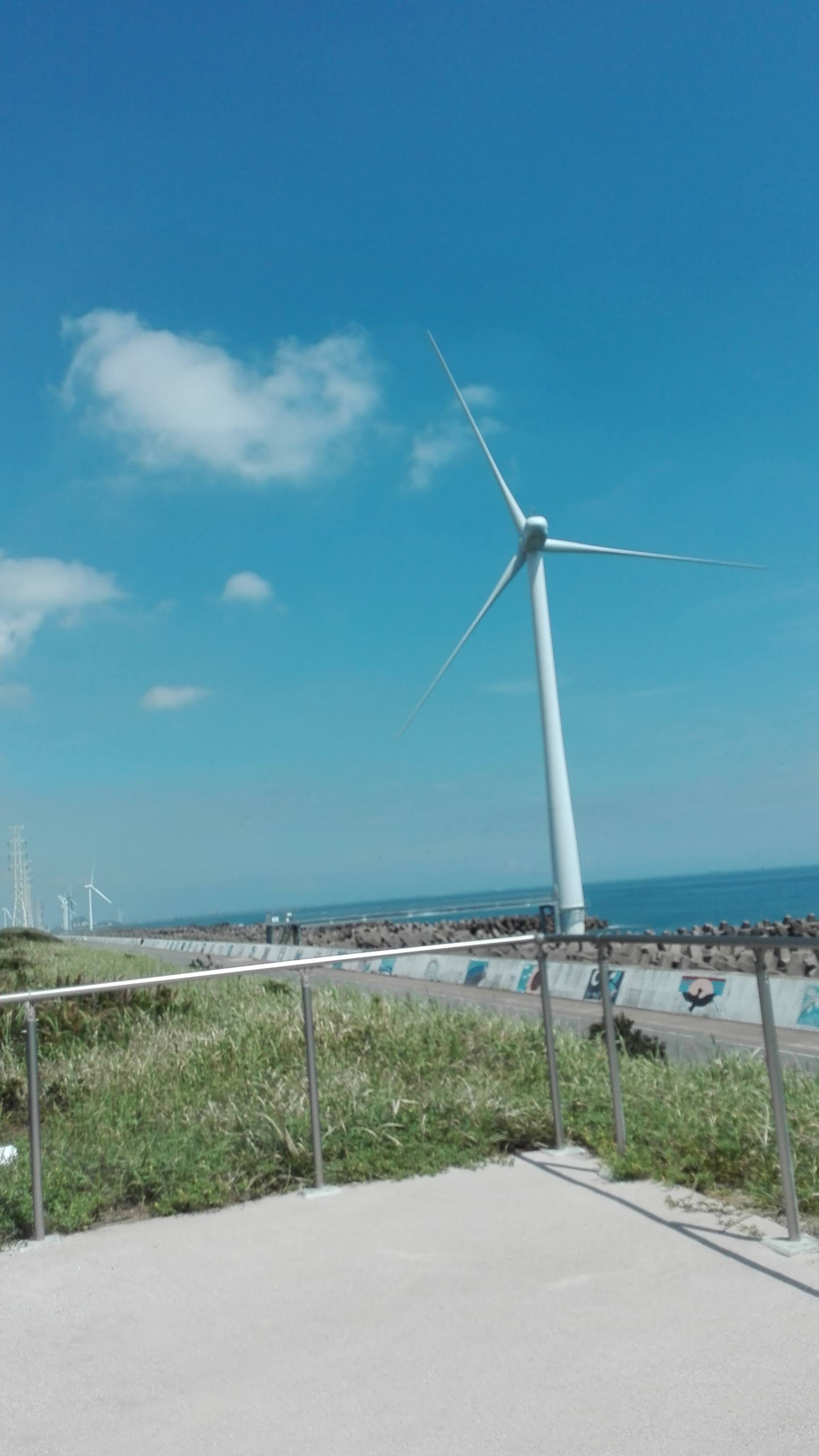 防波堤と風車が並ぶ海沿いの景色