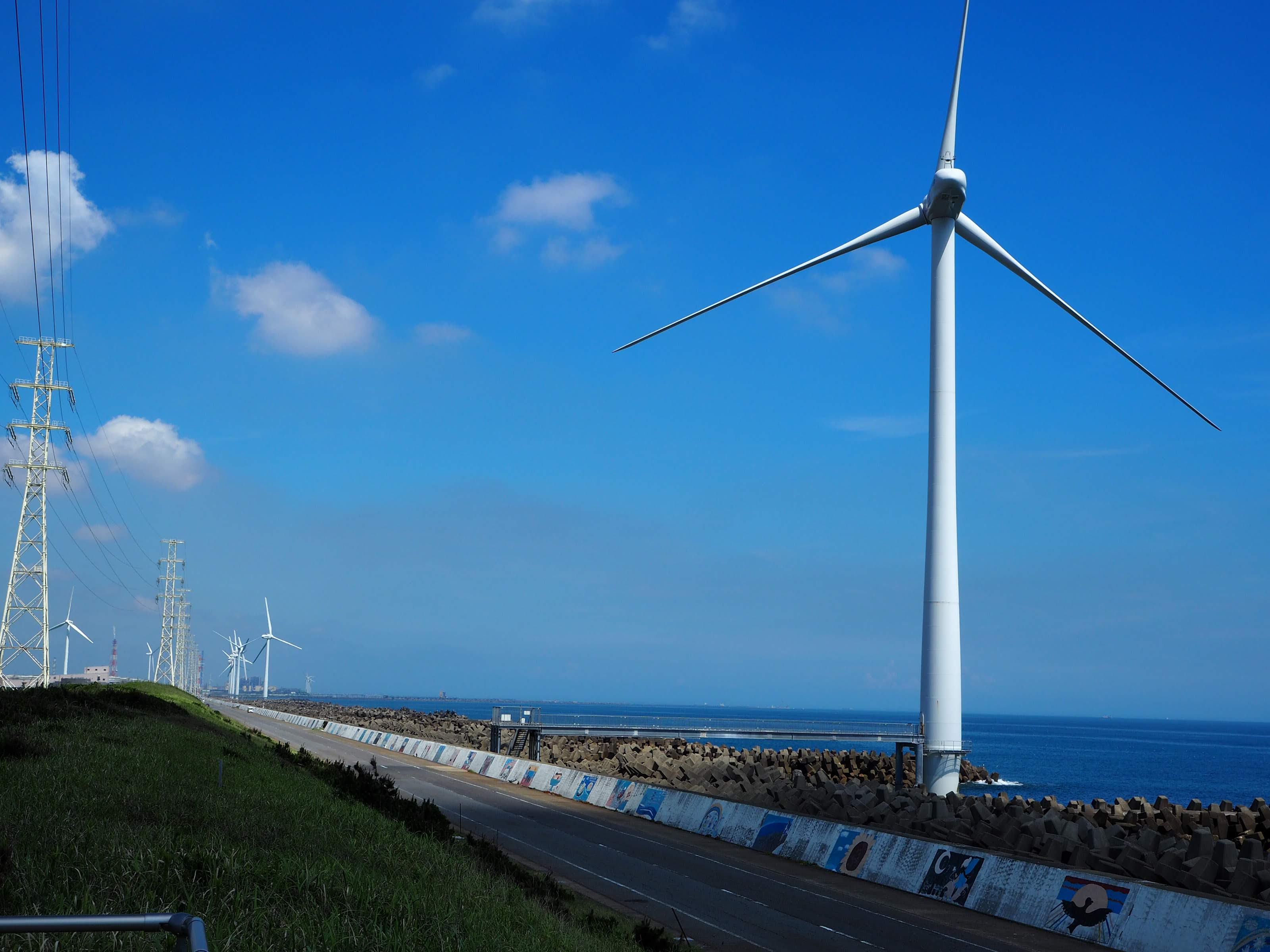 青空の下の風車と鉄塔