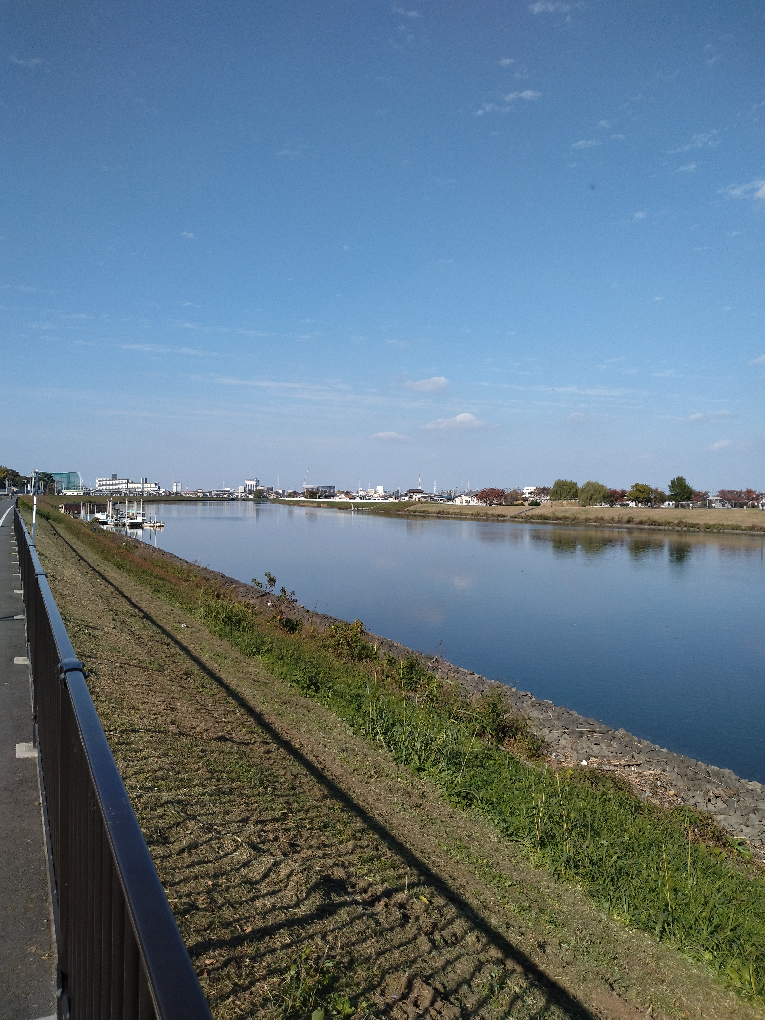 北綾瀬周辺の少し開けた郊外風景と道路の雰囲気を伝える一枚で、周囲の景色を楽しみながらも安全運転を意識したいシーンです。